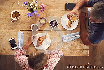 Overhead View Of Mature Couple In Coffee Shop Meeting Up In Socially Distanced Way Stock Photo