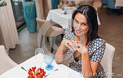 Overhead view of smilng young elegant woman wearing dress sitting in the restaurant looking to the camera. Caucasian female posing Stock Photo