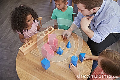 Overhead View Of Teacher And Pupils At Desk In Montessori School Stock Photo