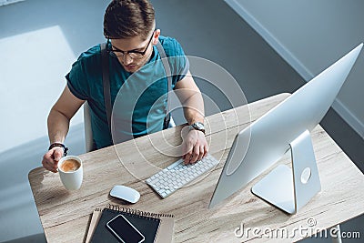 overhead view of young freelancer drinking coffee while working Stock Photo