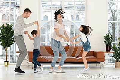Overjoyed active parents dancing with happy kids. Stock Photo