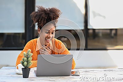 Overjoyed African American woman getting mail, read good news on laptop while sitting outdoor Stock Photo