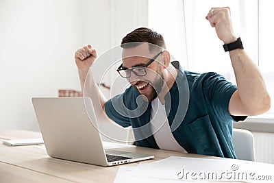 Overjoyed businessman wearing glasses looking at laptop screen in office Stock Photo