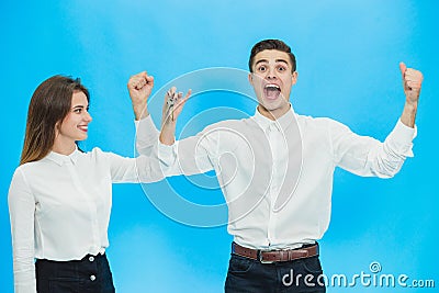 Overjoyed couple with kwys to their new apartments, raising hands up, ready to move as soon as possible. Stock Photo