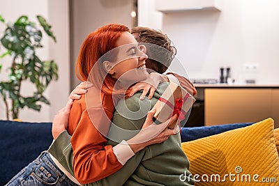 Overjoyed happy young woman holding gift box hugging husband feeling excited Stock Photo