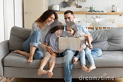 Overjoyed kids watching funny video on computer with parents. Stock Photo