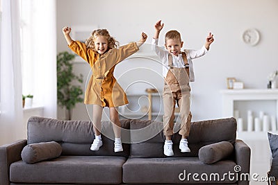 Overjoyed little children brother and sister jumping on sofa at home Stock Photo