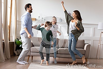 Overjoyed married couple dancing to favorite music with kids. Stock Photo