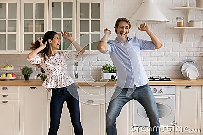 Overjoyed millennial couple dance in home kitchen Stock Photo