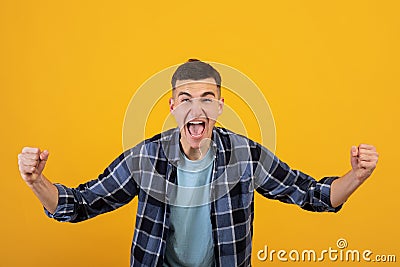 Overjoyed millennial guy screaming in excitement, gesturing YES with both hands on orange studio background Stock Photo