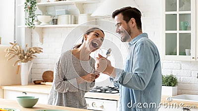 Overjoyed mixed race family spouse holding kitchenware, using as microphones. Stock Photo