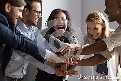 Overjoyed older asian businesswoman joining hands with young multiracial coworkers. Stock Photo