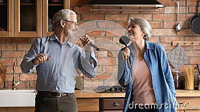 Overjoyed older senior couple having fun sing songs at kitchen Stock Photo