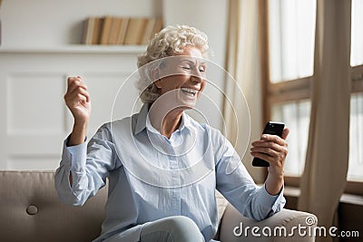 Overjoyed older woman looking at mobile phone screen. Stock Photo