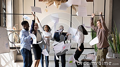 Overjoyed older and young business people throwing papers in air. Stock Photo