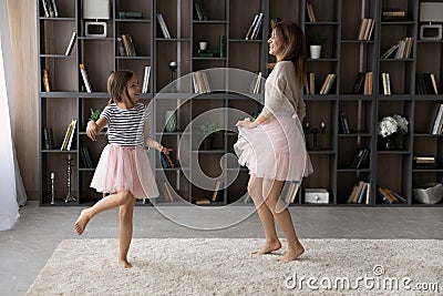 Overjoyed older and younger sisters dressed in pettiskirts dance together Stock Photo