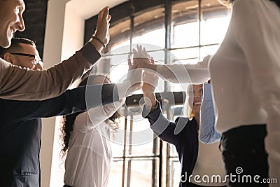 Overjoyed older and younger teammates joining hands in air. Stock Photo