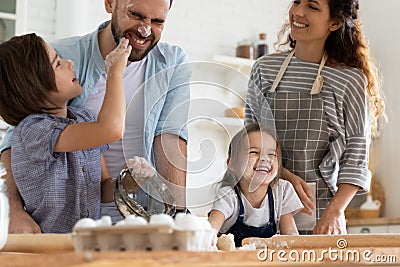 Overjoyed small children siblings spreading flour on laughing parents. Stock Photo