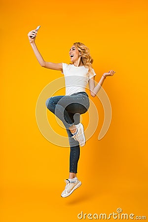 Overjoyed woman jumping and taking selfie on phone Stock Photo
