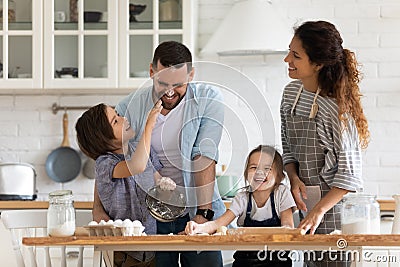 Overjoyed parents with little kids have fun cooking in kitchen Stock Photo