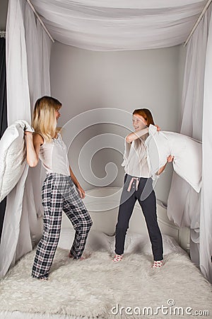 Overjoyed young mom and happy little daughter have fun engaged in pillow fight in bedroom, excited mother and small preschooler Stock Photo