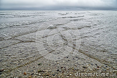 Overlapping, intersecting waves on seashore with dramatic cloudy sky. Natural background, pattern, texture of water. Interference Stock Photo