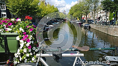 Overlooking one of the canals of Amsterdam in the Netherlands. The seat and the handlebars of the bike in the frame Stock Photo