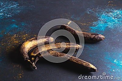 Overripe yellow-black bananas on dark blue background. Minimalist Stock Photo