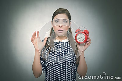 Overslept shocked woman with red alarm clock on gray background. Oversleep. Latecomer. Stock Photo