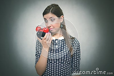 Overslept shocked woman with red alarm clock on gray background. Oversleep. Latecomer. Stock Photo