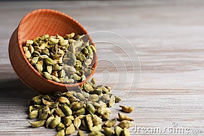 Overturned bowl with dry cardamom pods on wooden table, closeup. Space for text Stock Photo