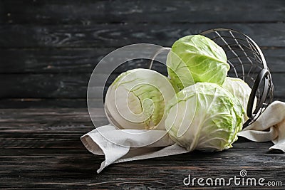 Overturned metal basket with fresh cabbages on wooden table Stock Photo