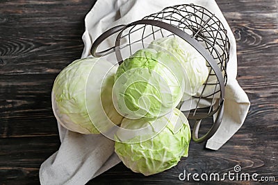 Overturned metal basket with fresh cabbages on wooden table Stock Photo