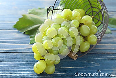 Overturned metal basket with ripe juicy grapes on wooden table Stock Photo