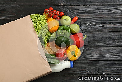 Overturned paper bag and groceries on black wooden background Stock Photo