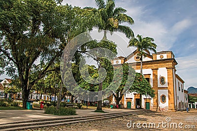 Overview of old colored church, garden with trees and cobblestone street in Paraty. Stock Photo