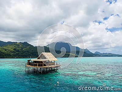 Lonely overwater bungalow of black pearl farmers. Blue azure turquoise lagoon. Raiatea island, French Polynesia. Aerial view. Stock Photo