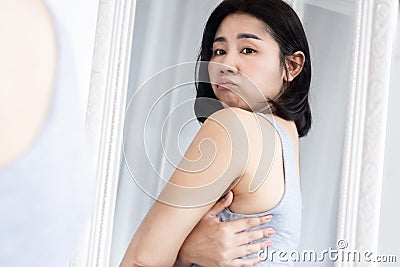 Asian woman unhappy with back bra bulge fat , checking upper back fat in a mirror Stock Photo