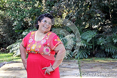 Overweight brunette Latina adult woman in her 50s is happy and proud of her roots wearing traditional Mexican embroidered dress Stock Photo