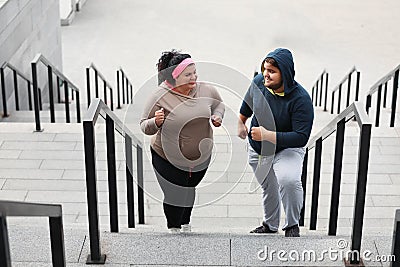 Overweight couple running up stairs together Stock Photo