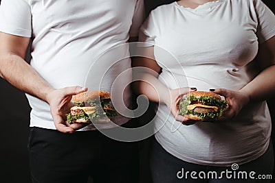 Overweight fat couple snack with tasty hamburgers Stock Photo