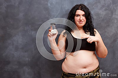 Overweight fat woman pointing on a bottle of slimming pills. Wei Stock Photo