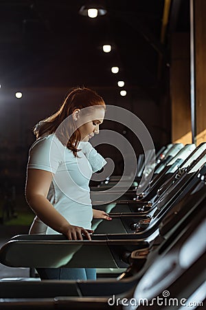 Overweight girl training on treadmill in gym Stock Photo