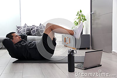 Overweight latino adult man exercises inside his home in his living room via computer online to be healthy Stock Photo