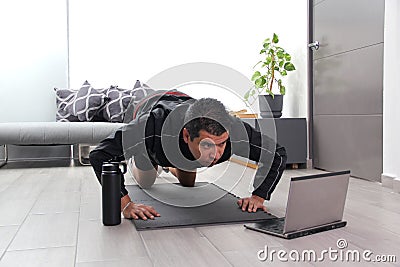Overweight latino adult man exercises inside his home in his living room via computer online to be healthy Stock Photo