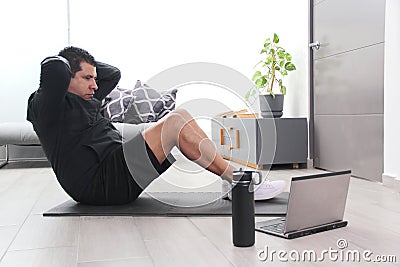 Overweight latino adult man exercises inside his home in his living room via computer online to be healthy Stock Photo