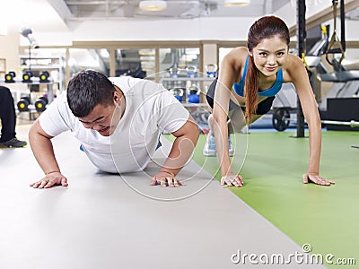 Overweight man and slim girl exercising together Stock Photo