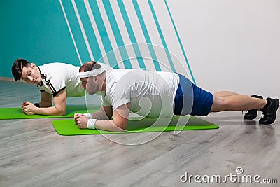 An overweight man is stressed to the limit while standing in the bar during fitness group classes Stock Photo