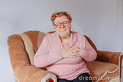 Overweight and Overwhelmed upset Woman Suffers Heart Attack on Sofa, Stock Photo
