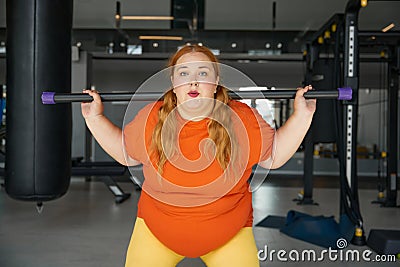 Overweight woman having fitness workout squatting with body bar training equipment Stock Photo